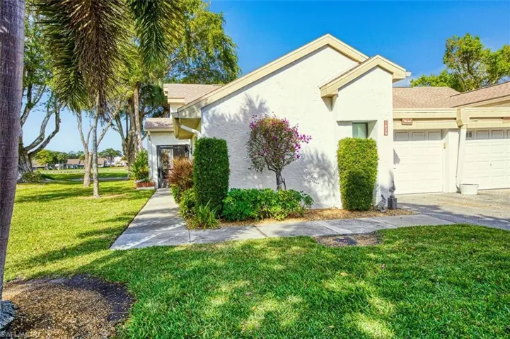 View of front of home featuring stucco siding, a garage, a front yard, and driveway