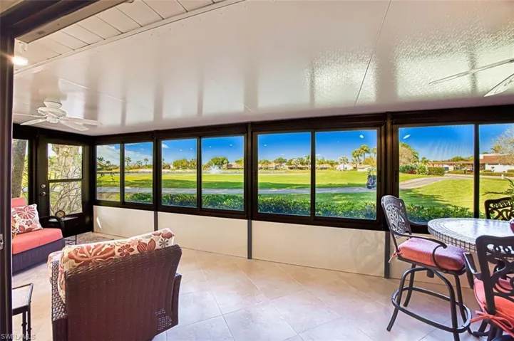 Sunroom with golf course view and a ceiling fan