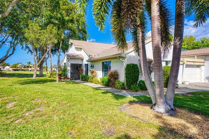 View of front of property with stucco siding, a front yard, a garage, and roof with shingles