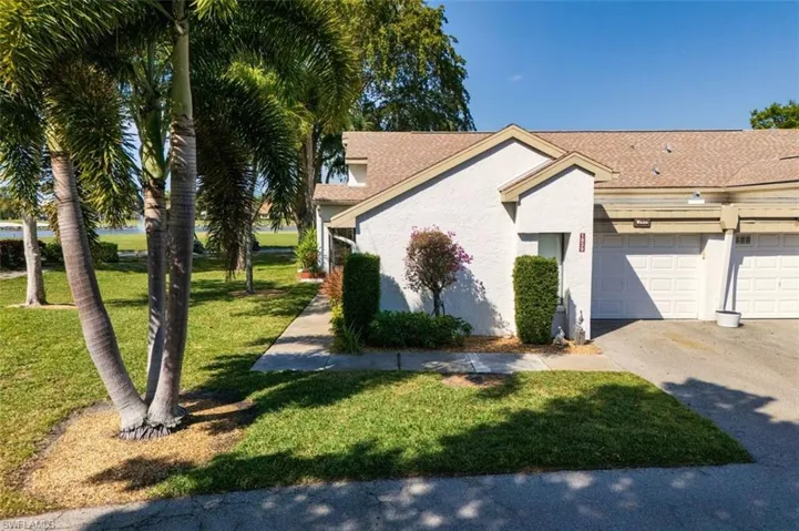 View of front of home featuring a front lawn, stucco siding, a garage, driveway, and a shingled roof