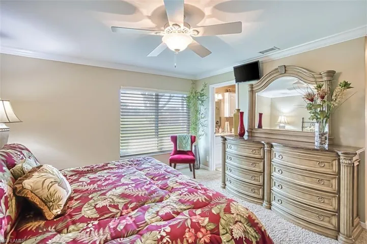 Master Bedroom with crown molding, connected bathroom, a ceiling fan, and light colored carpet
