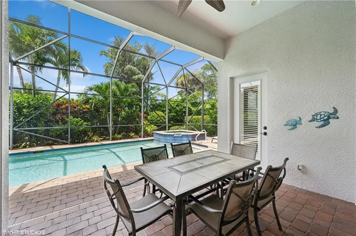 View of pool with an in ground hot tub, a patio, and glass enclosure