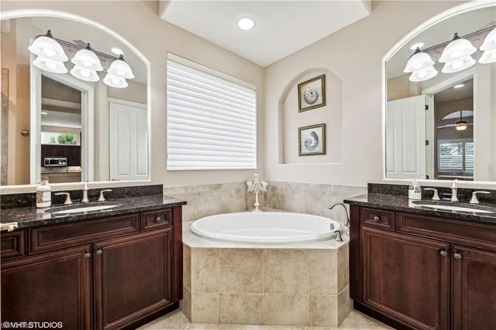 Bathroom with a relaxing tiled tub, tile patterned floors, and double sink vanity