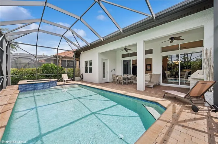 View of swimming pool featuring an in ground hot tub, a patio, ceiling fan, and a lanai