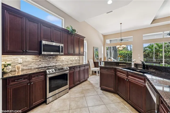 Kitchen featuring dark stone counters, stainless steel appliances, light tile patterned floors, and sink