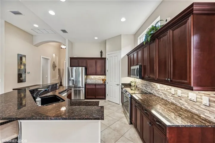 Kitchen featuring sink, dark stone counters, tasteful backsplash, and stainless steel appliances