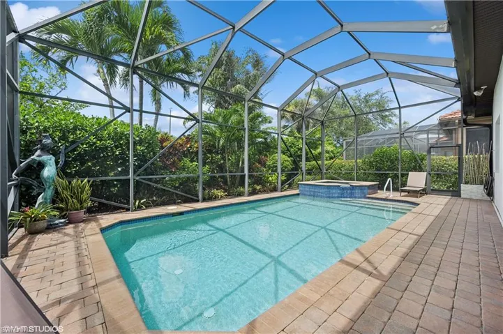 View of pool with a patio, an in ground hot tub, and glass enclosure