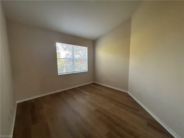Spare room with vaulted ceiling and dark wood finished floors