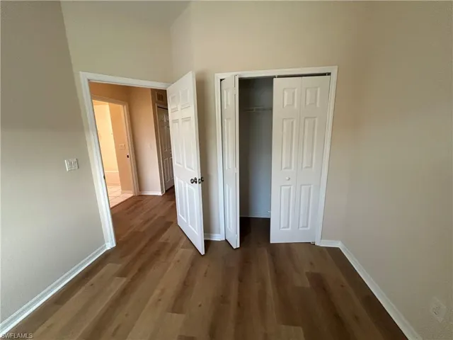 Unfurnished bedroom featuring a closet and dark wood-type flooring