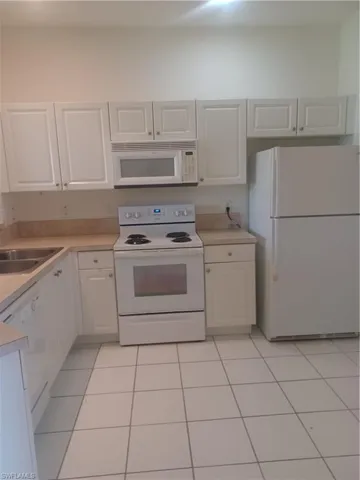 Kitchen with white appliances, white cabinets, light countertops, and light tile patterned floors