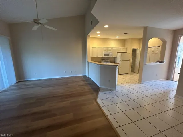 Kitchen featuring white cabinetry, light tile patterned floors, open floor plan, a peninsula, and white appliances