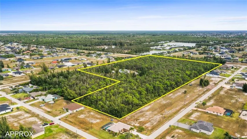 Aerial view of residential area with property boundaries highlighted and a nearby body of water