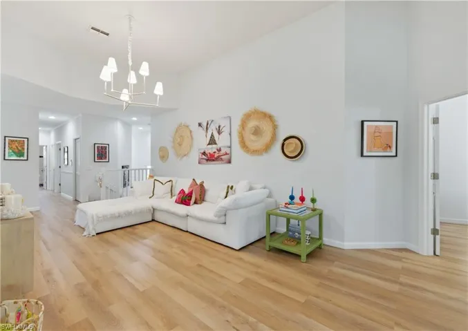 Living room featuring a high ceiling, a chandelier, and light wood-style floors