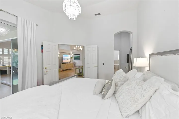 Bedroom with suspended lighting, arched walkways, a high ceiling, a closet, and connected bathroom