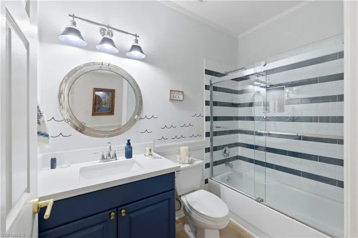 Bathroom featuring vanity, crown molding, and shower / bath combination with glass door