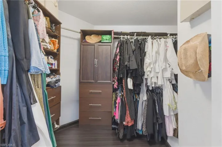 Walk in closet with dark wood-style flooring