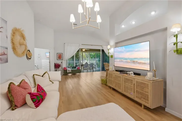 Living area featuring light wood-type flooring, suspended lighting, and vaulted ceiling