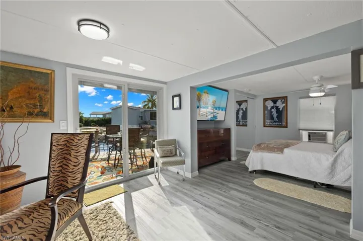 Bedroom featuring access to outside, hardwood / wood-style flooring, cooling unit, and ceiling fan
