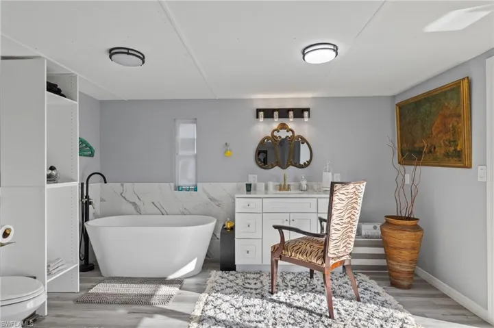 Bathroom with hardwood / wood-style floors, tile walls, toilet, and vanity