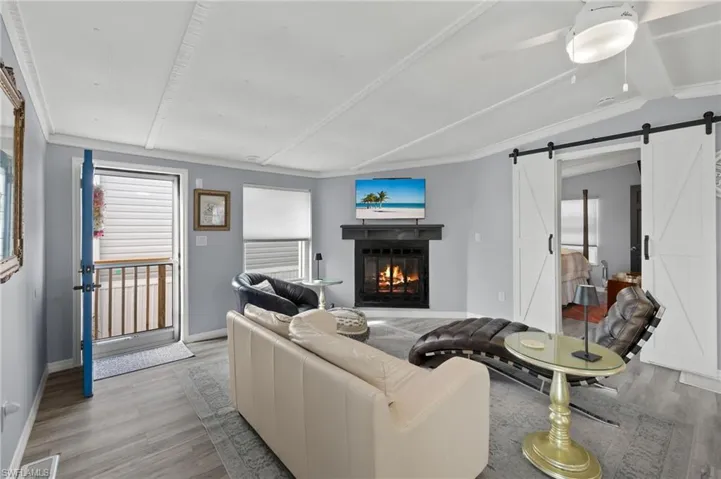 Living room featuring ornamental molding, a barn door, lofted ceiling, and light wood-type flooring