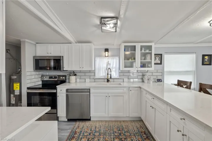 Kitchen featuring appliances with stainless steel finishes, sink, light hardwood / wood-style floors, decorative backsplash, and white cabinetry