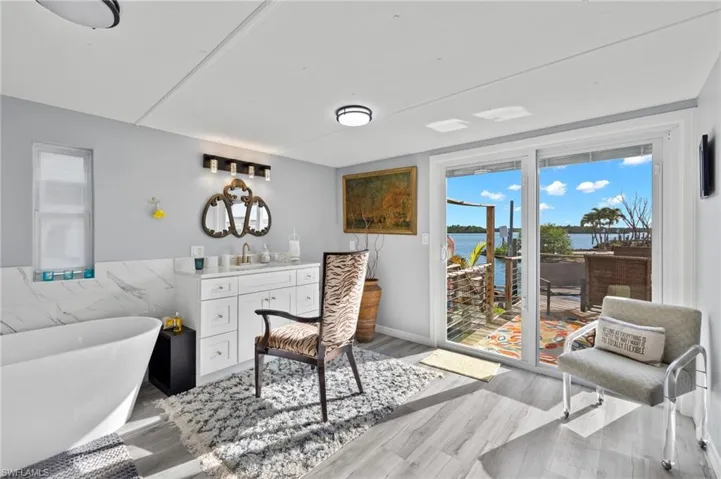 Living room with light hardwood / wood-style floors, a water view, and sink