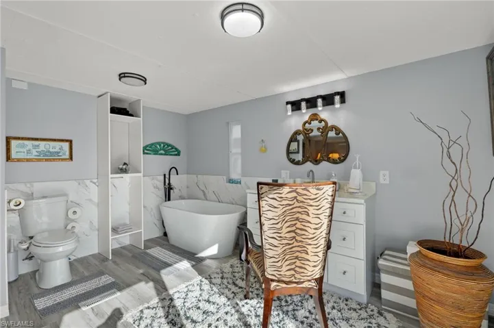 Bathroom with vanity, hardwood / wood-style flooring, tile walls, a bathing tub, and toilet