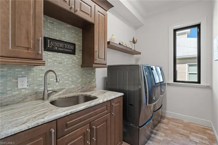 Clothes washing area featuring cabinets, independent washer and dryer, sink, and ornamental molding