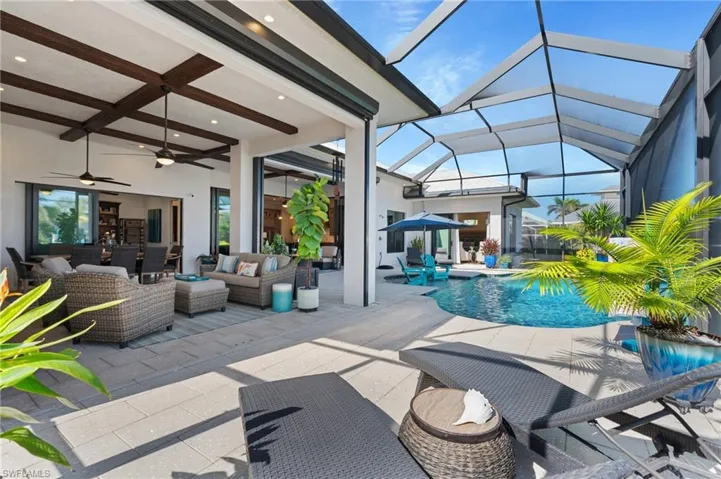 View of pool with an outdoor living space, a patio area, ceiling fan, and a lanai