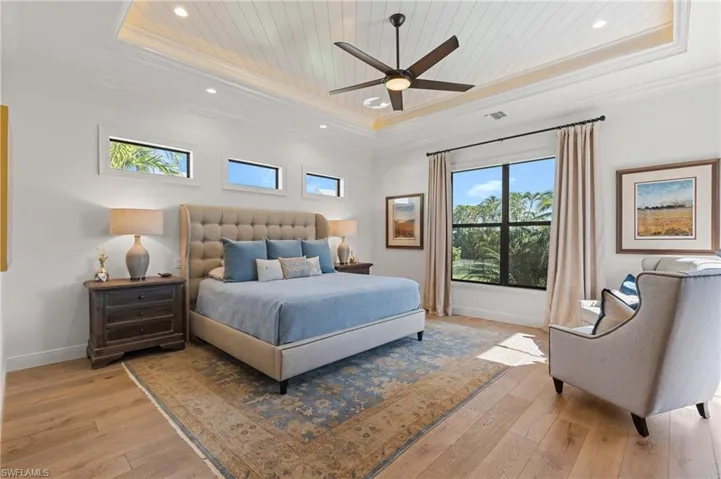 Bedroom featuring ceiling fan, a raised ceiling, light wood-type flooring, wood ceiling, and ornamental molding