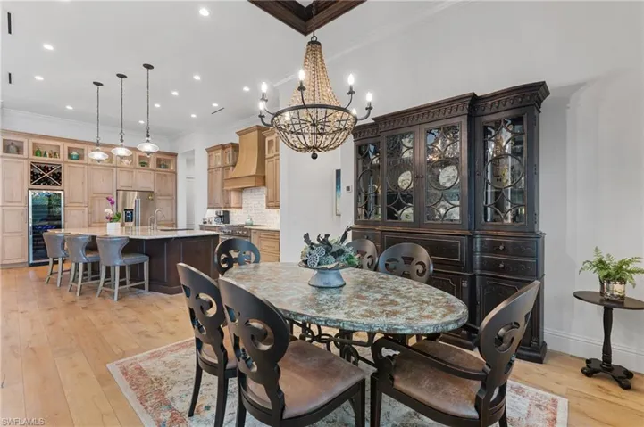 Dining room featuring ornamental molding, beverage cooler, sink, a chandelier, and light hardwood / wood-style floors