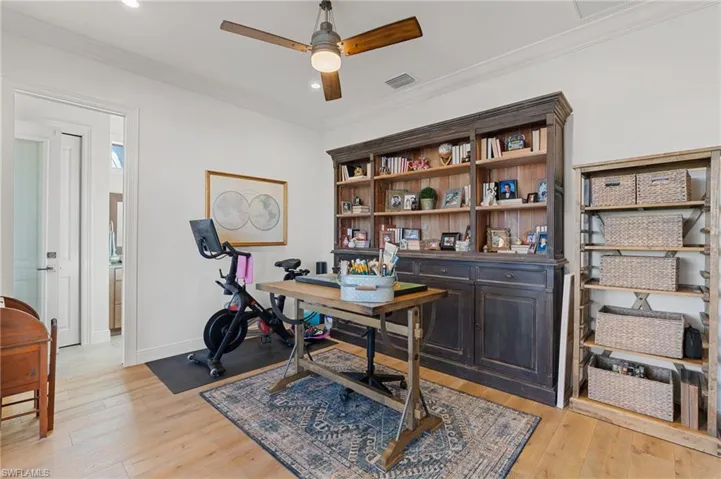 Home office with ceiling fan, ornamental molding, and light hardwood / wood-style flooring