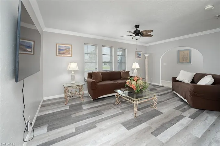 Living area featuring arched walkways, crown molding, and a ceiling fan