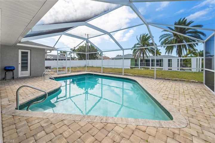 View of pool with a lanai and a patio area.  Please note the fence has been finished since photos.