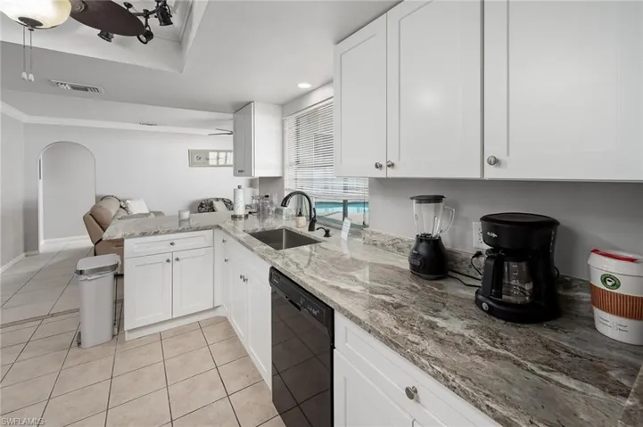 Kitchen with white cabinetry, dishwasher, and ornamental molding