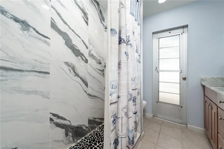 Full bath with vanity, a shower, and light tile patterned floors
