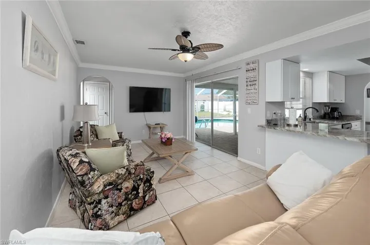 Family room featuring crown molding, a ceiling fan, and light tile patterned floors