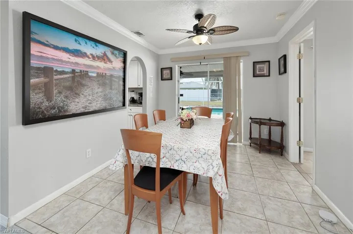 Dining space featuring a light tile patterned flooring, arched walkways, crown molding, and ceiling fan