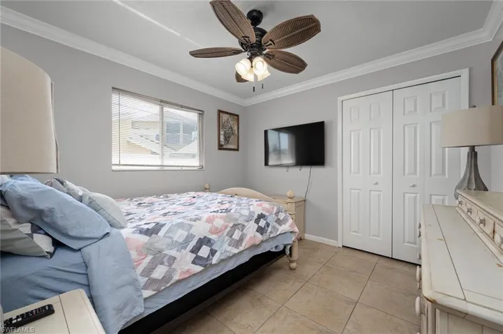 Bedroom featuring crown molding, a closet, ceiling fan, and light tile patterned flooring