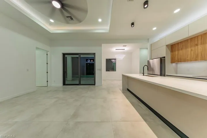 Unfurnished living room with recessed lighting, a tray ceiling, and concrete flooring