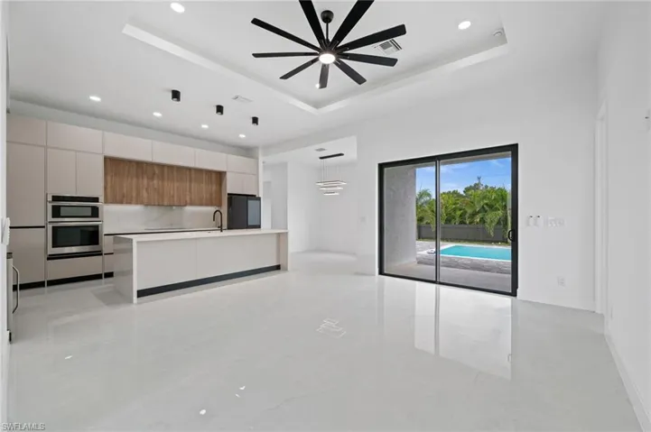 Unfurnished living room featuring a raised ceiling, recessed lighting, and a ceiling fan