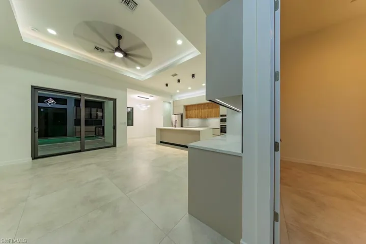 Unfurnished living room featuring a ceiling fan, a tray ceiling, recessed lighting, and concrete floors