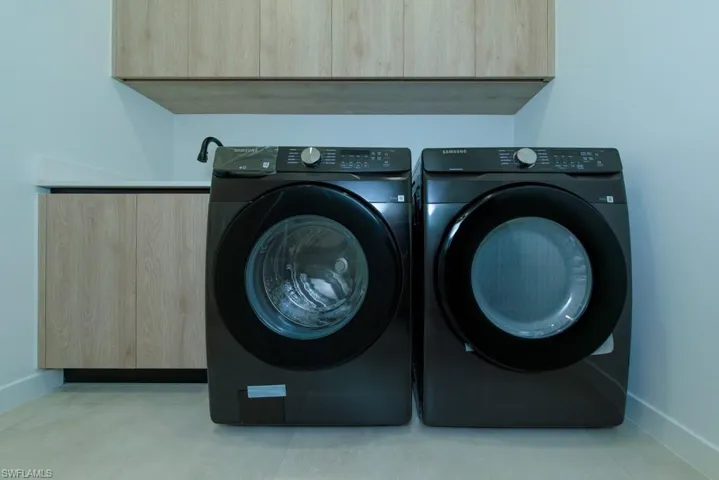 Laundry area featuring separate washer and dryer and cabinet space