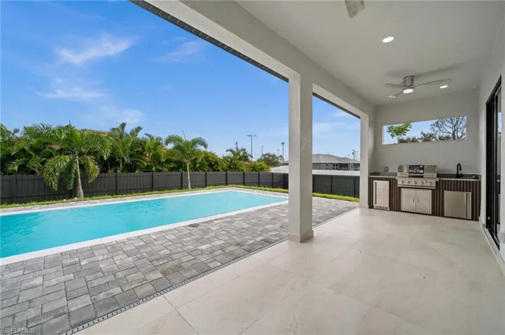 View of pool with an outdoor kitchen, a patio, a fenced backyard, and ceiling fan