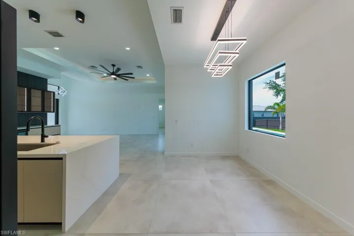 Unfurnished dining area featuring a tray ceiling, recessed lighting, ceiling fan, and light tile patterned floors