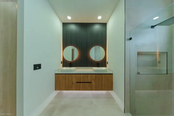 Full bathroom with a stall shower, double vanity, recessed lighting, and light tile patterned floors