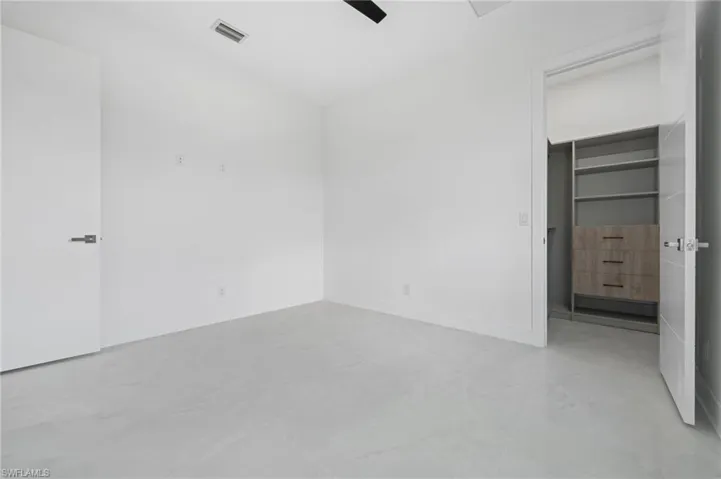 Unfurnished bedroom with a spacious closet and ceiling fan