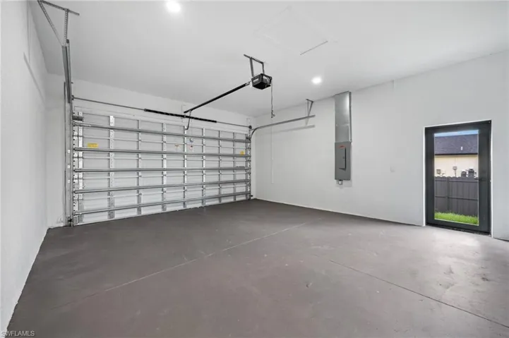 Garage with electric panel, recessed lighting, and a garage door opener