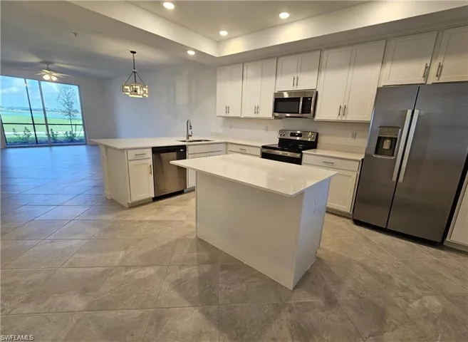 Kitchen featuring stainless steel appliances, white cabinets, pendant lighting, and a peninsula