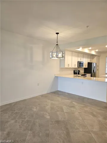 Kitchen featuring white cabinets, a peninsula, stainless steel appliances, and hanging lights